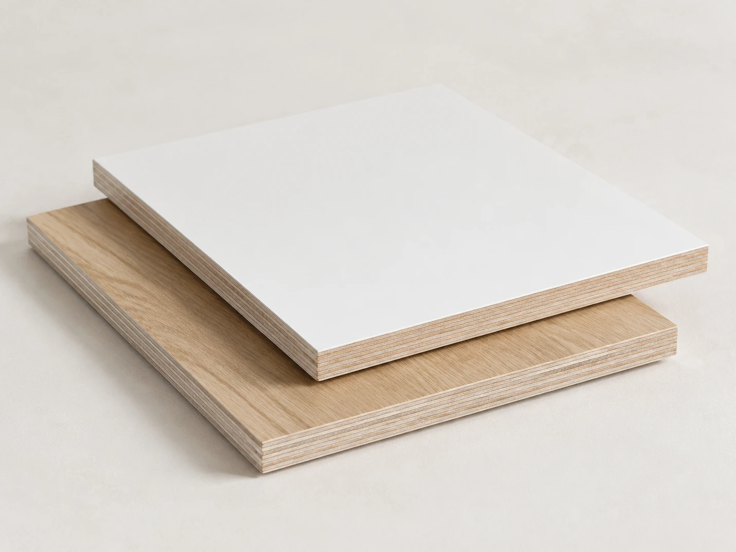 Two melamine-faced plywood panels, one white and one light oak woodgrain, offset to show their layered plywood edges